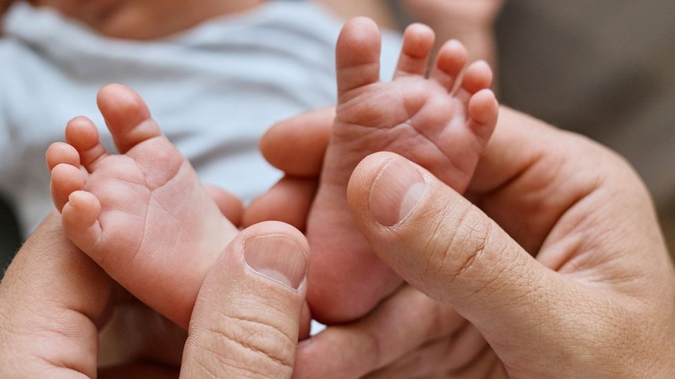 father hands holding newborn feet