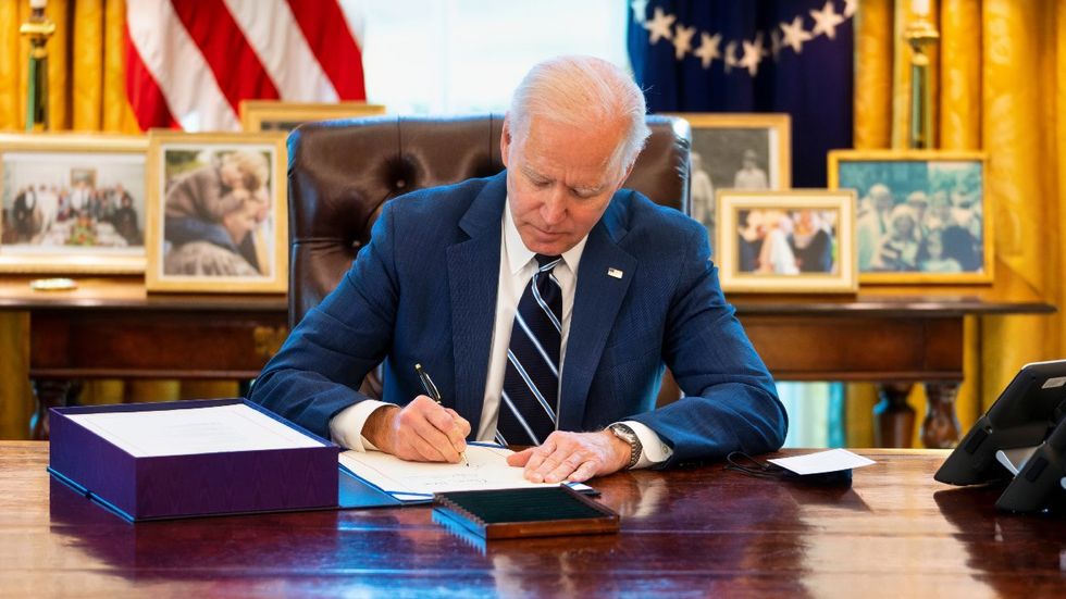 Joe Biden signing a document at the White House