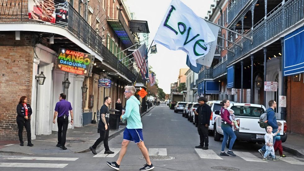 Man runs with a love flag down Bourbon Street on January 2, 2025 in New Orleans, Louisiana, the day after an attack by a man driving a truck down Bourbon street in the French Quarter