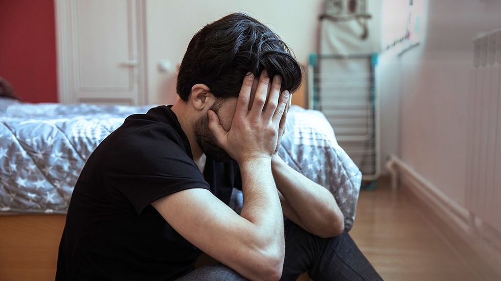 sad man bedroom floor hands over face