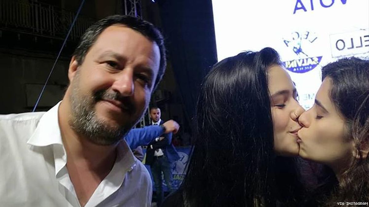 Two women photobomb anti-gay Italian politician with same-sex kiss selfie.
